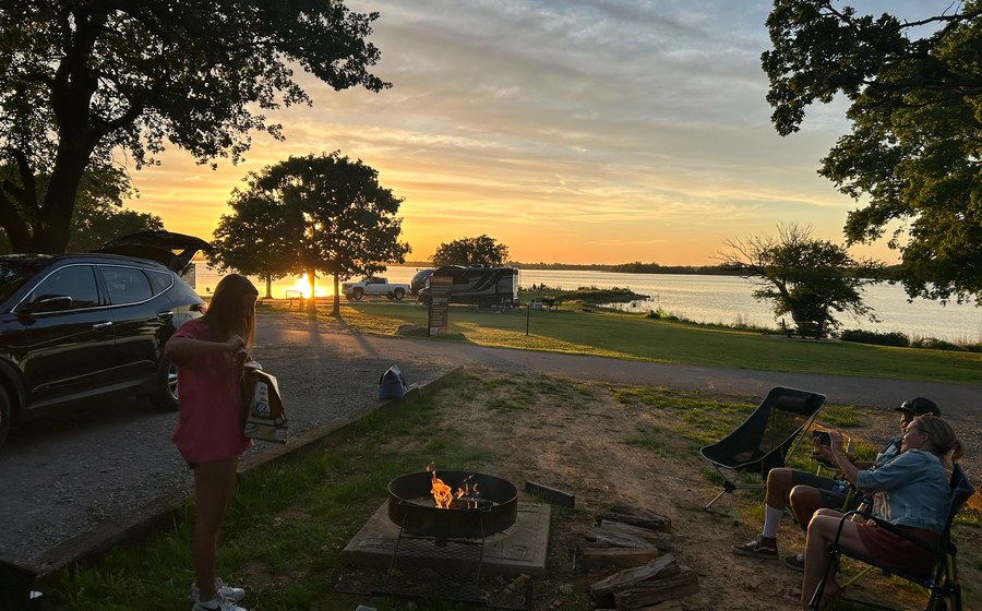 Campfire at a lakeside campsite during sunset