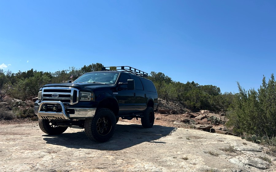Black Ford Excursion parked on a rocky overlook